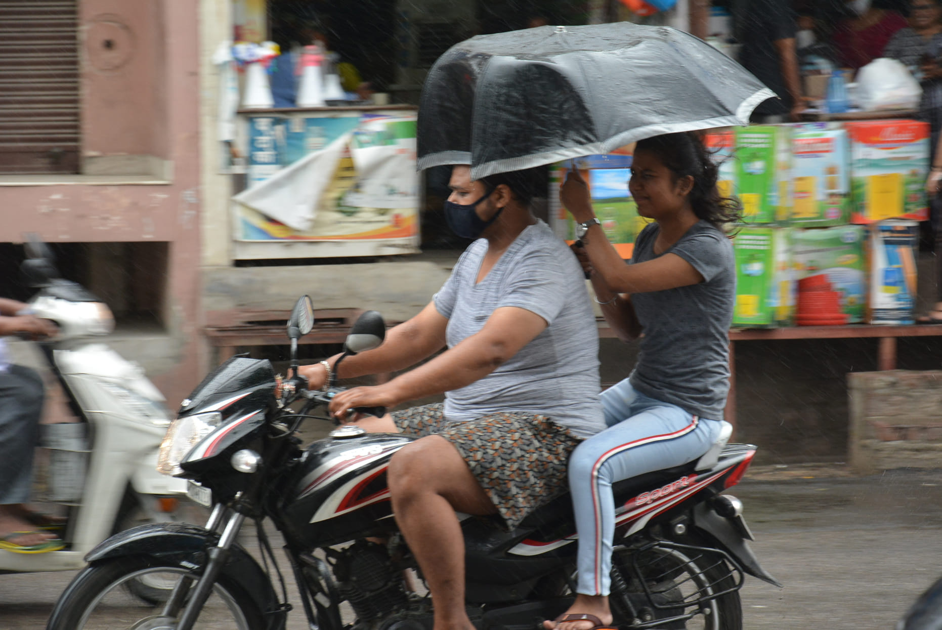 बारिश में छाता लेकर गंतव्य को जाते स्कूटी सवार। बारिश में छाता लेकर गंतव्य को जाते स्कूटी सवार।