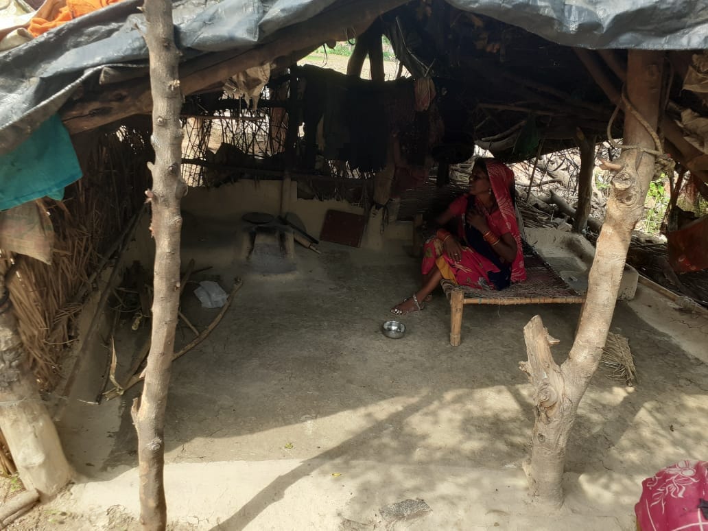 झोपड़ी में बैठी आदिवासी महिला