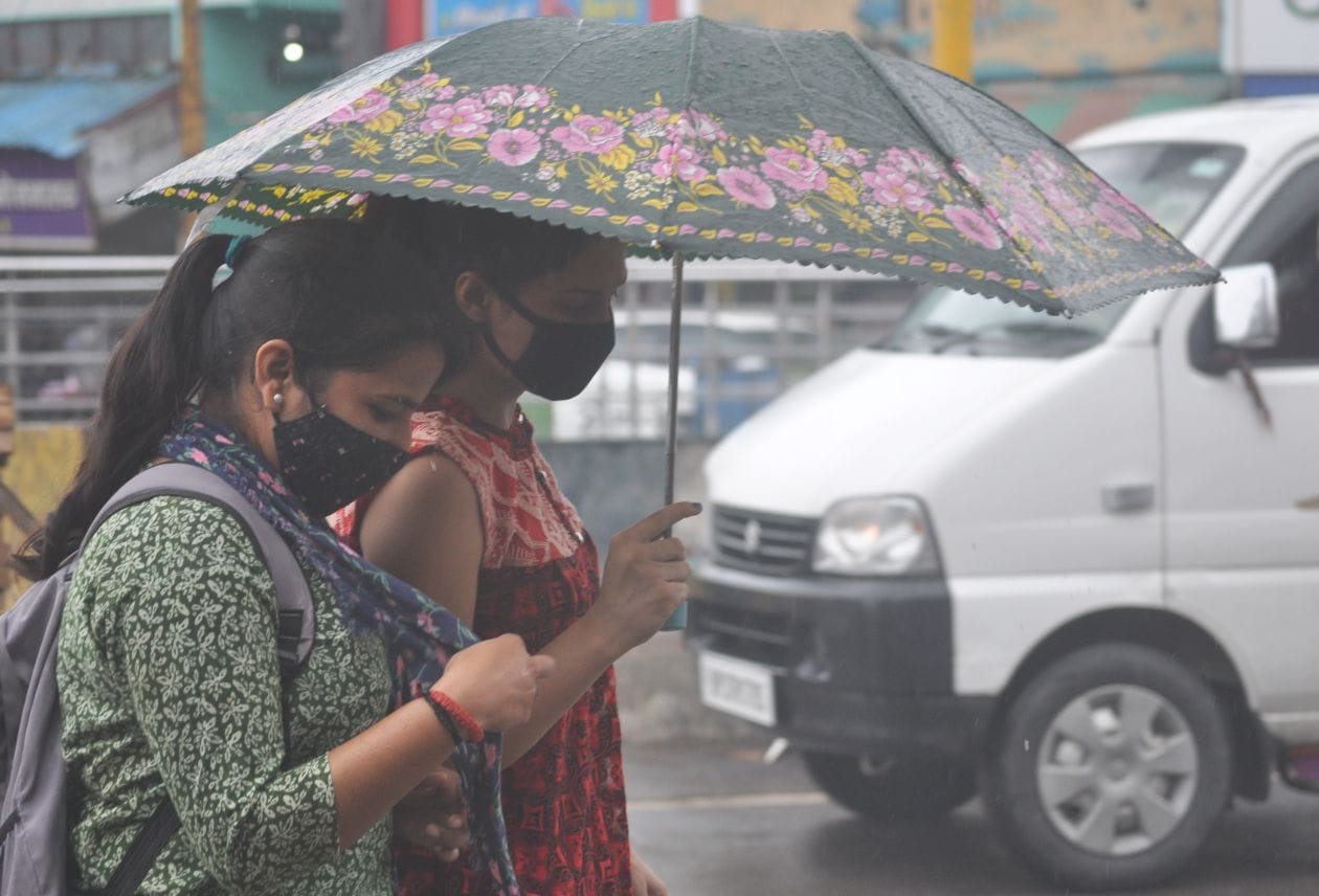 बारिश में छाता लगाकर जाती युवतिया बारिश में छाता लगाकर जाती युवतिया