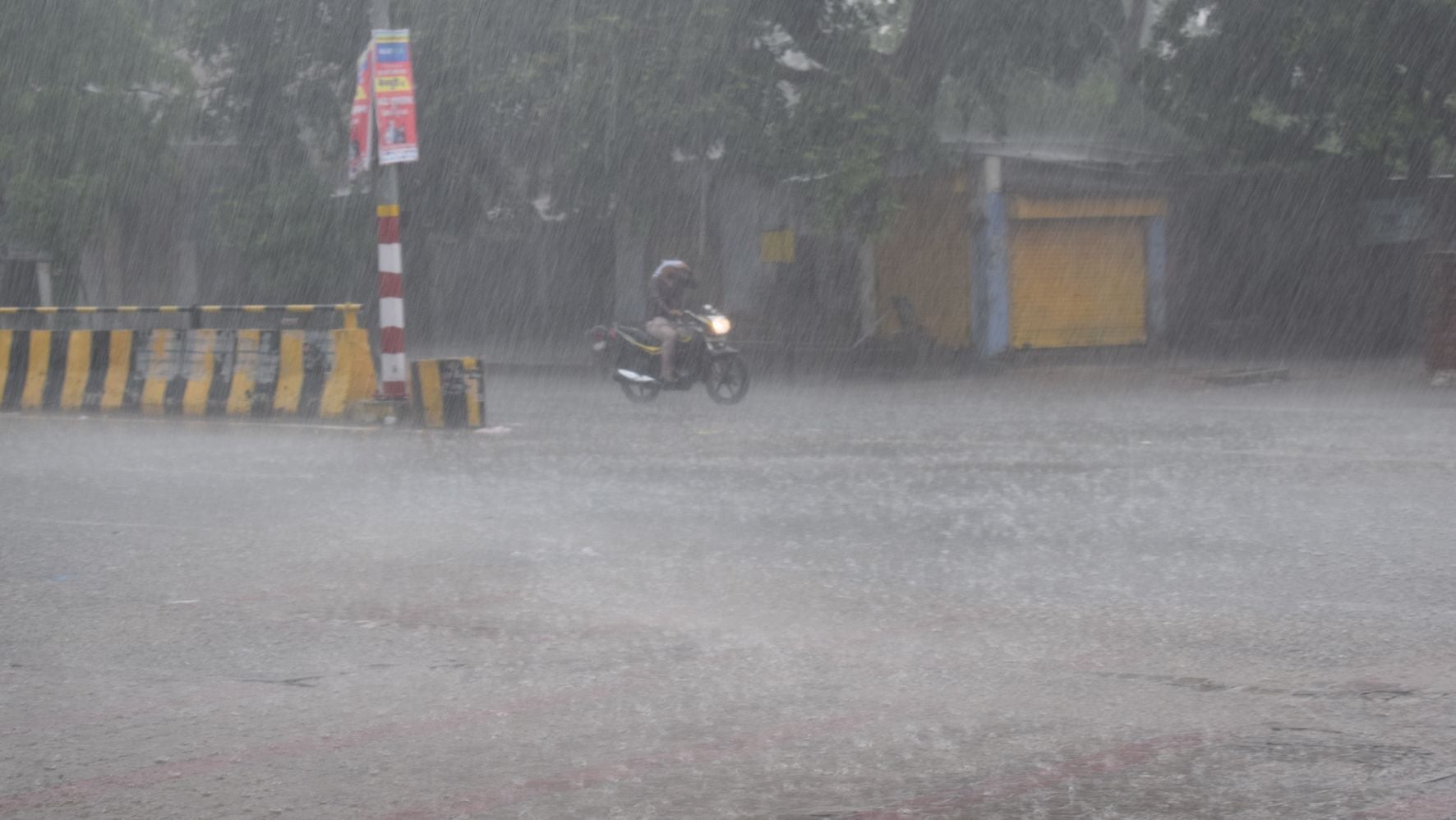 मुसलाधार बारिश के बीच गुजरते लोग मुसलाधार बारिश के बीच गुजरते लोग