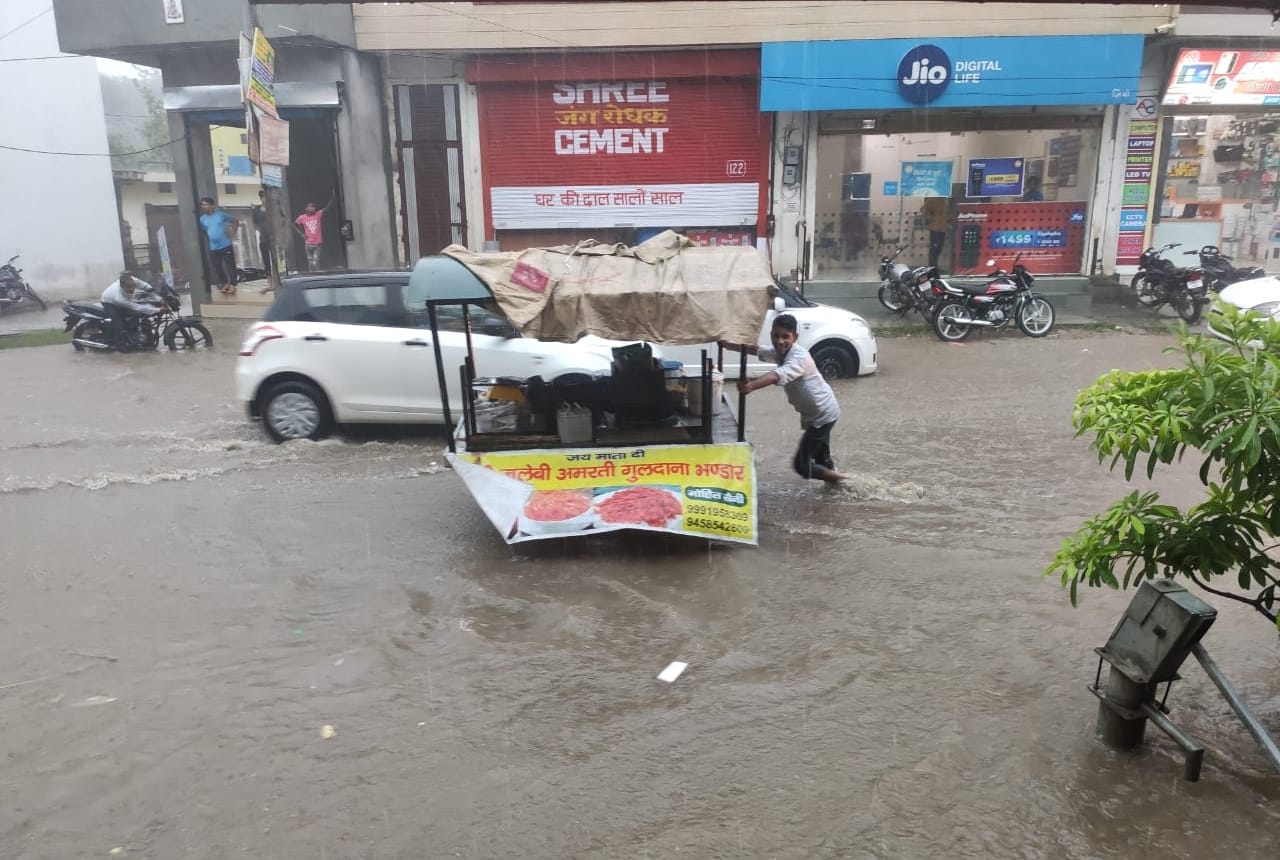 छछरौली बाजार में सड़क पर जमा पानी व गुजरता रेहड़ी चालक। संवाद छछरौली बाजार में सड़क पर जमा पानी व गुजरता रेहड़ी चालक। संवाद