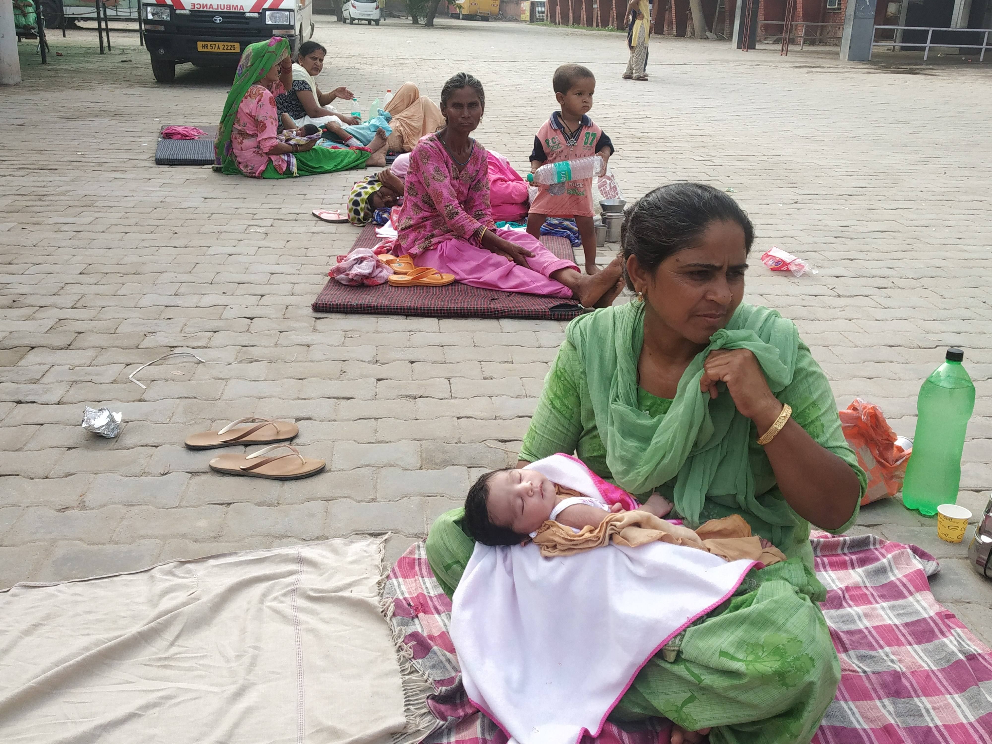 भवन के बाहर नवजात को लेकर बैठी महिलाएं भवन के बाहर नवजात को लेकर बैठी महिलाएं