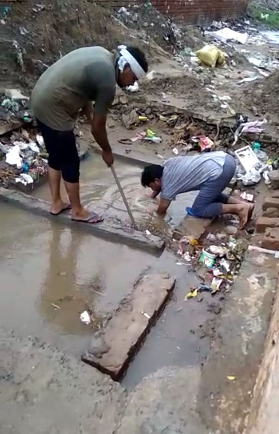 रिचार्जिंग बोर से कचरा हटाते नगर परिषद के कर्मचारी।