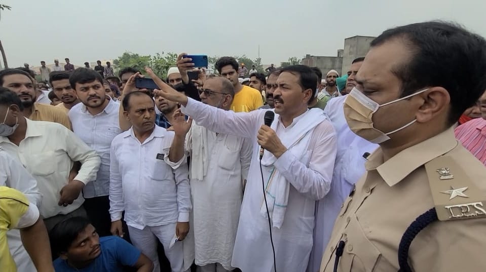जीशान के पोस्टमार्टम के दौरान लोगों से शांति बनाने की अपील करते समुदाय के नेता।   संवाद