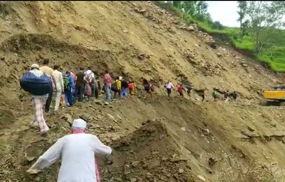 टनकपुर-पिथौरागढ़ राष्ट्रीय राजमार्ग पर खतरनाक रास्ते से पैदल जाते फंसे मुसाफिर। फोटो: विज्ञप्त?