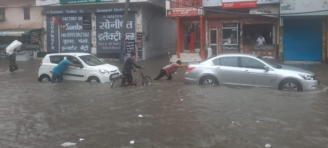 गोहाना रोड पर भरे पानी में बंद पड़ी गाडिय़ों को धक्का लगाते वाहन चालक। संवाद गोहाना रोड पर भरे पानी में बंद पड़ी गाडिय़ों को धक्का लगाते वाहन चालक। संवाद