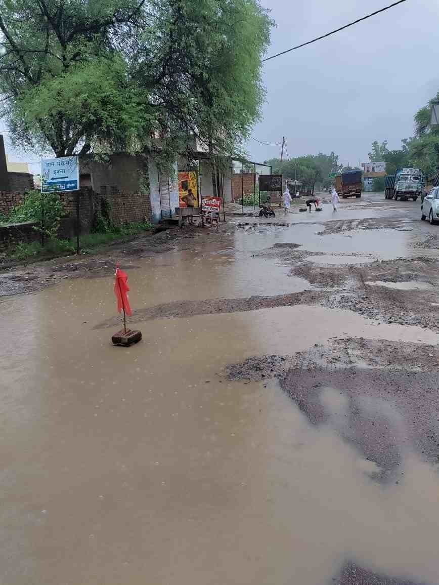 पुलिस द्वारा सड़क पर बने गड्ढे में लगाया गया झंडा। पुलिस द्वारा सड़क पर बने गड्ढे में लगाया गया झंडा।