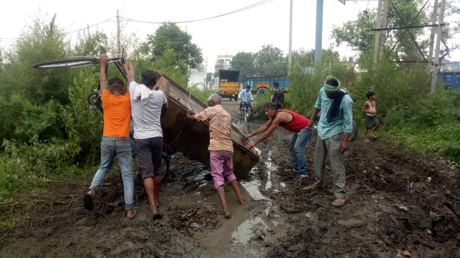 कीचड़ व गड्ढ़ों के कारण पलटा रिक्शा सीधी करते लोग।  संवाद