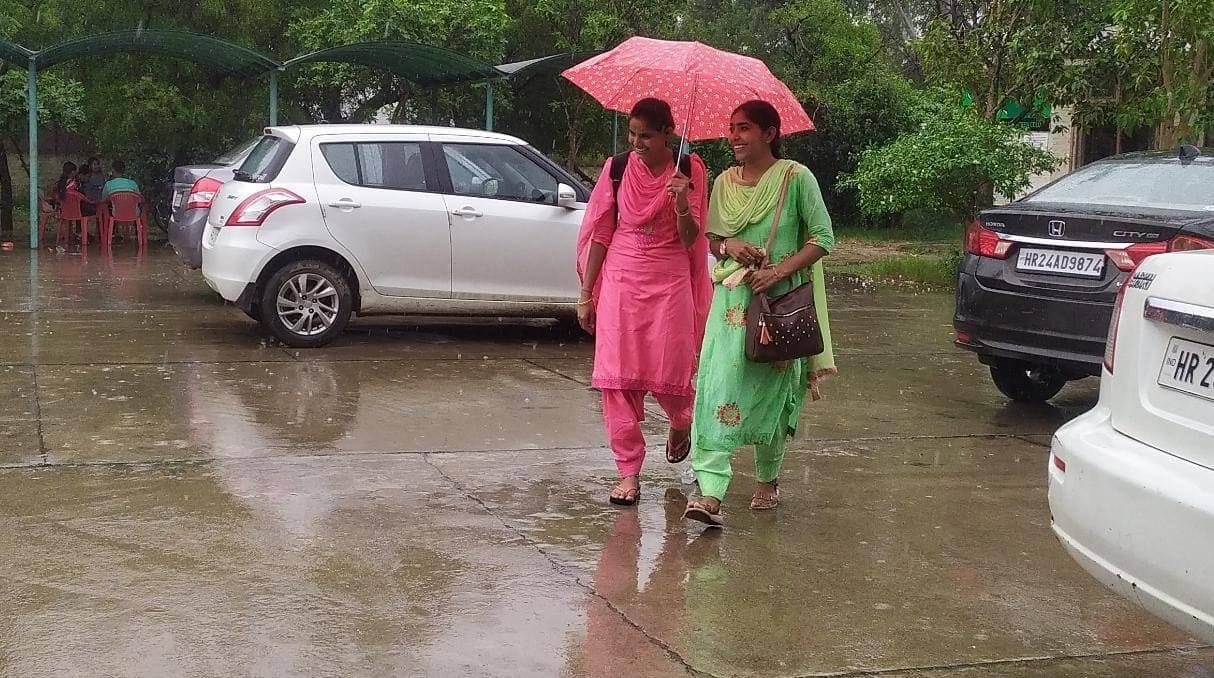 बारिश से बचने के लिए छाता लेकर जाती युवतियां संवाद बारिश से बचने के लिए छाता लेकर जाती युवतियां संवाद