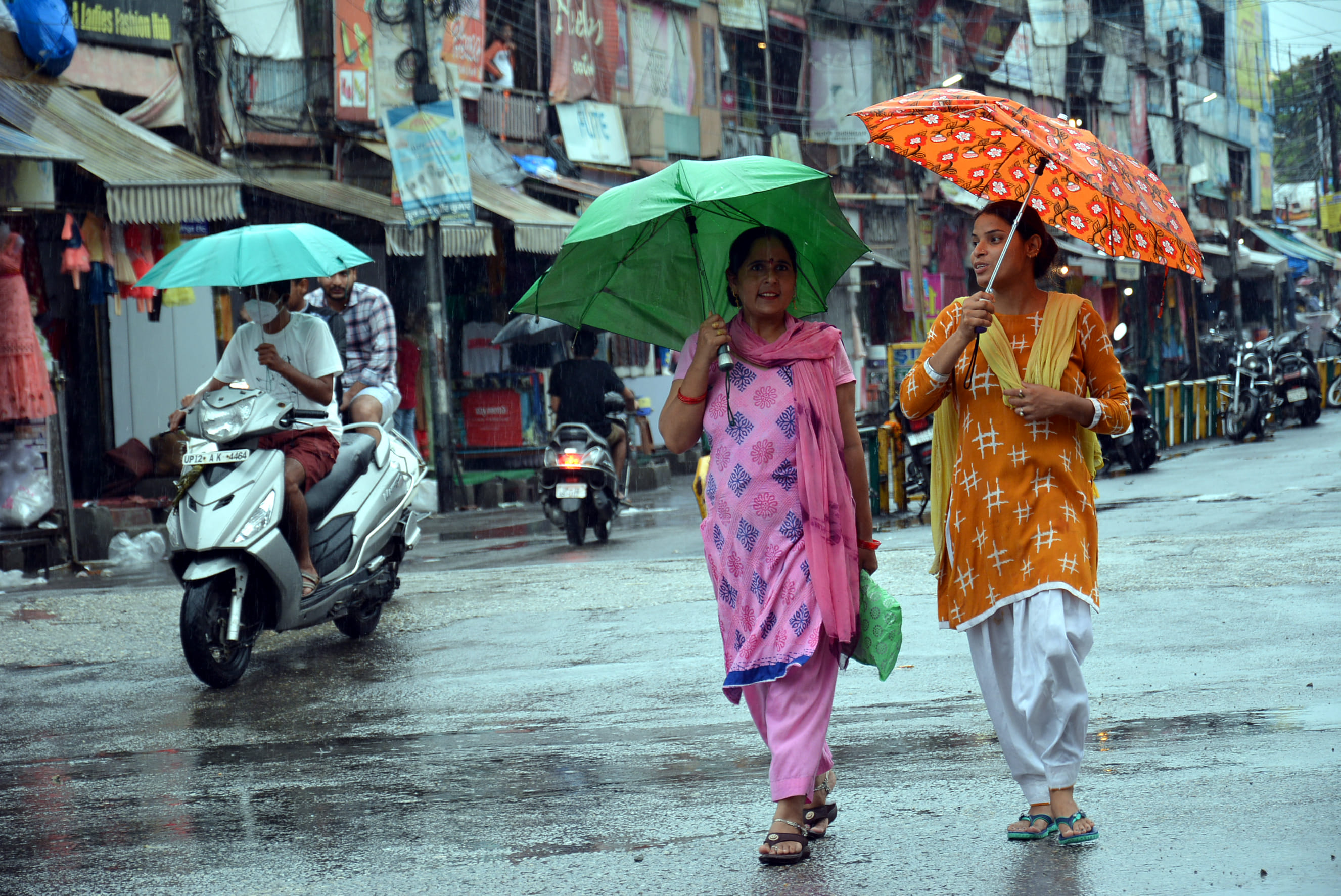 रिमझिम बारिश में छाता लेकर गंतव्य को जाती महिलाएं। रिमझिम बारिश में छाता लेकर गंतव्य को जाती महिलाएं।