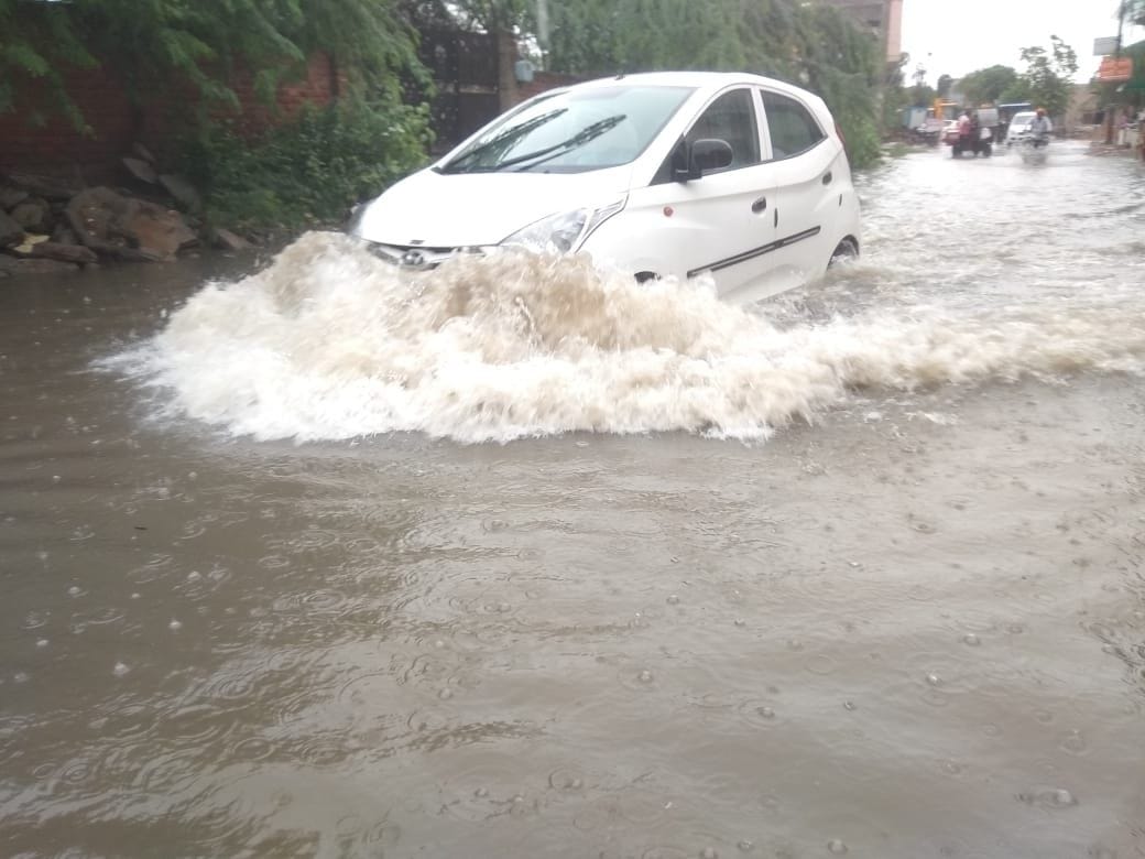 बारिश के पानी से निकलती गाड़ी। संवाद