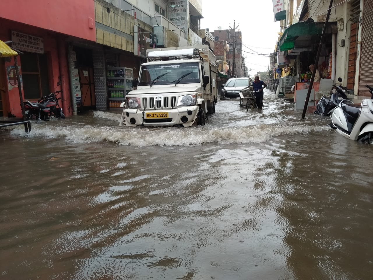 भारी जलभराव के बीच नदी मौहल्ला से निकलते वाहन। संवाद भारी जलभराव के बीच नदी मौहल्ला से निकलते वाहन। संवाद