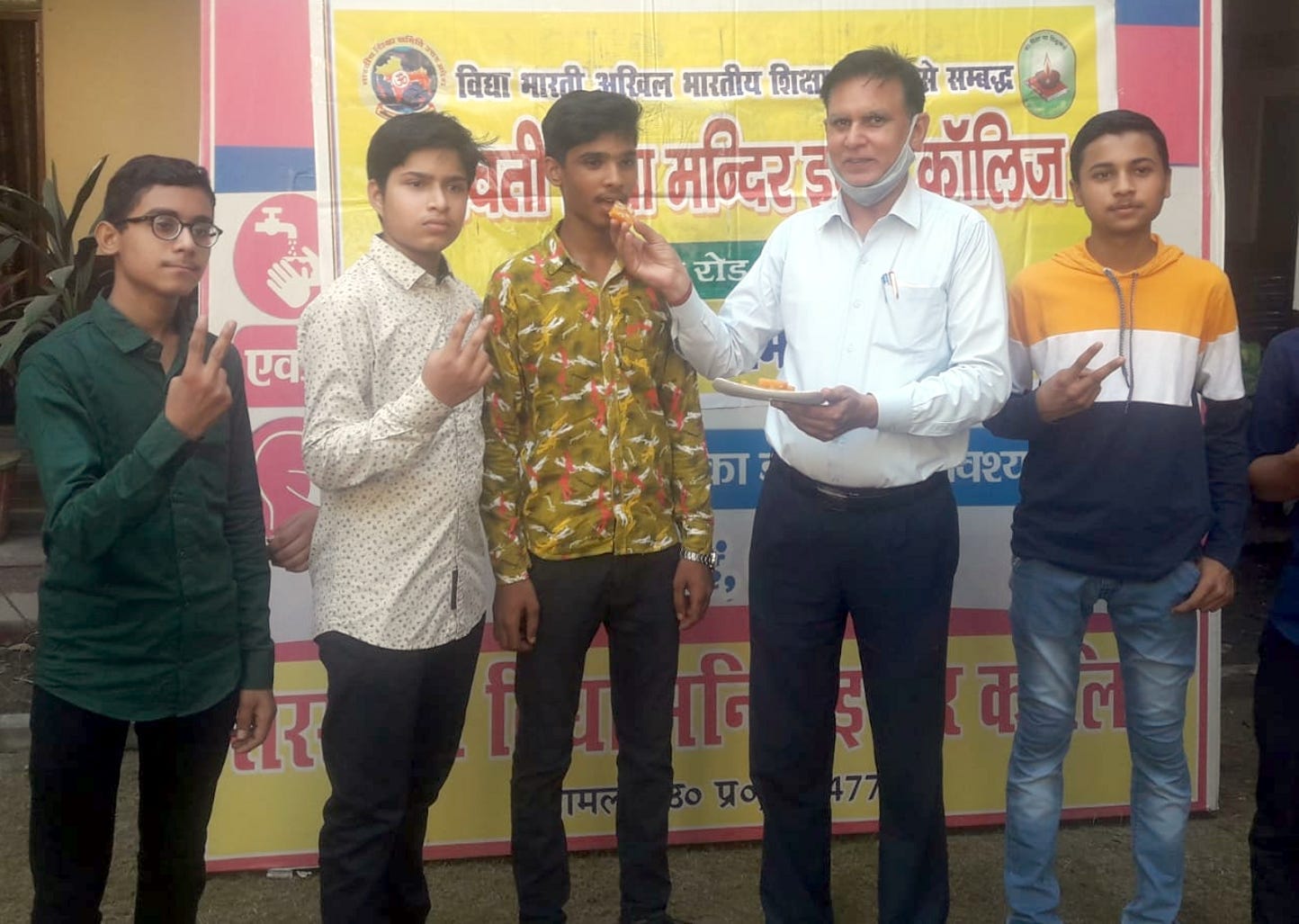 शामली सरस्वती विद्या मन्दिर इंटर कॉलेज  में हाई स्कूल के टॉपर छात्र निखिल को मिठाई खिलाते प्रधान?