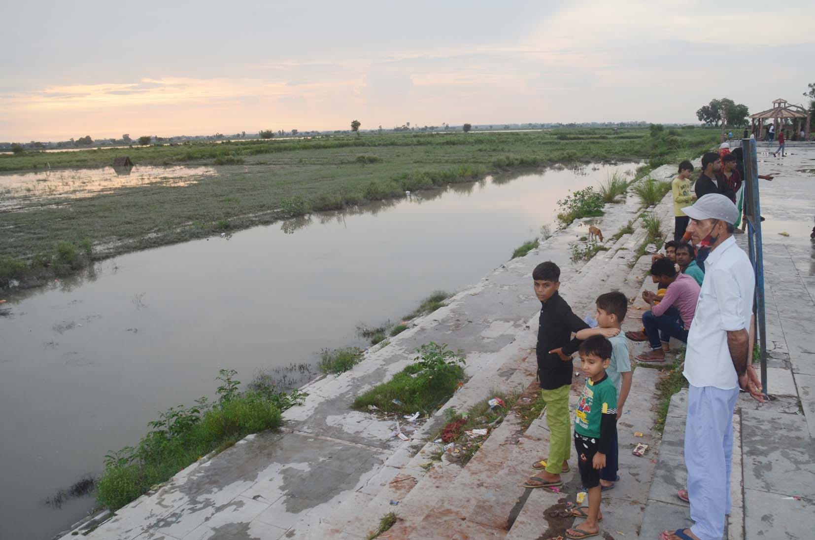बागपत के पक्काघाट पर यमुना का बढ़ता जलस्तर देखते लोग