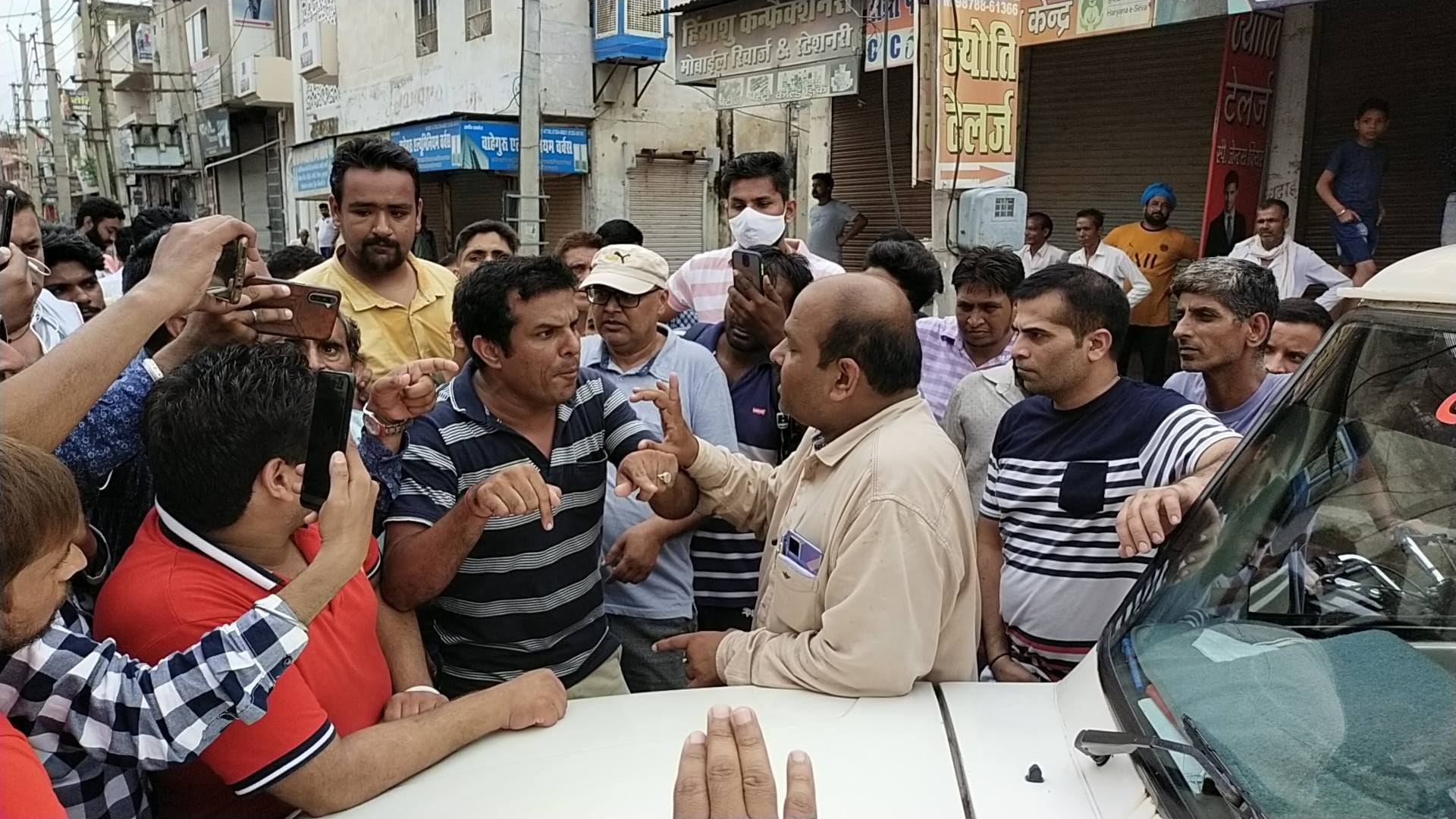 जेई को खरी-खोटी सुनाते धर्मशाला रोड के दुकानदार।
