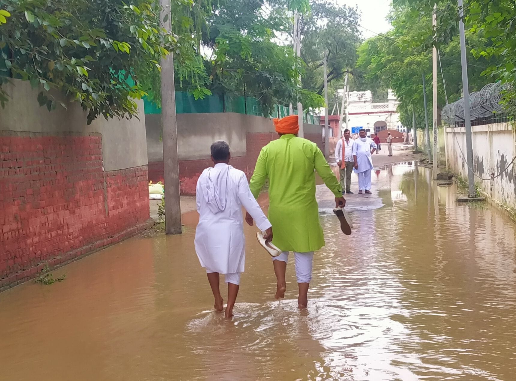 हाथ में जूतियां उठाकर रेस्ट हाउस पहुंचने के लिए पानी से गुजरते लोग। हाथ में जूतियां उठाकर रेस्ट हाउस पहुंचने के लिए पानी से गुजरते लोग।
