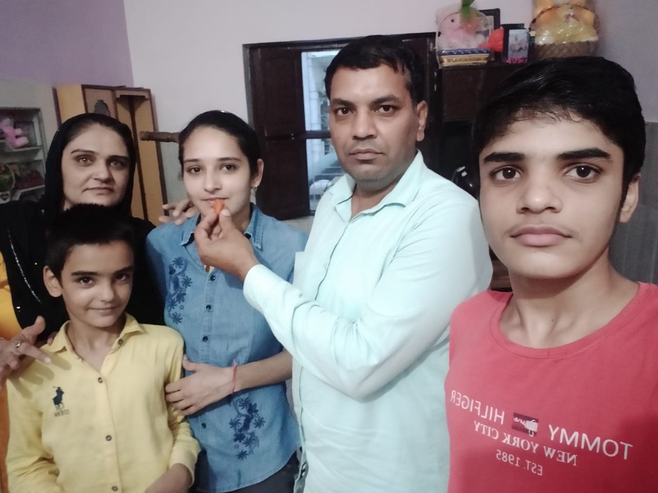 जिले में अव्वल स्थान हासिल करने पर नैंसी को मिठाई खिलाते परिजन।