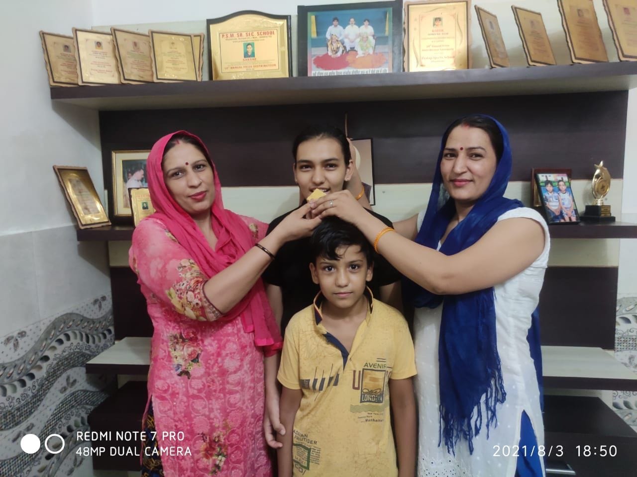 जिले में अव्वल रहने वाली लाडली साक्षी को मिठाई खिलाते परिजन।