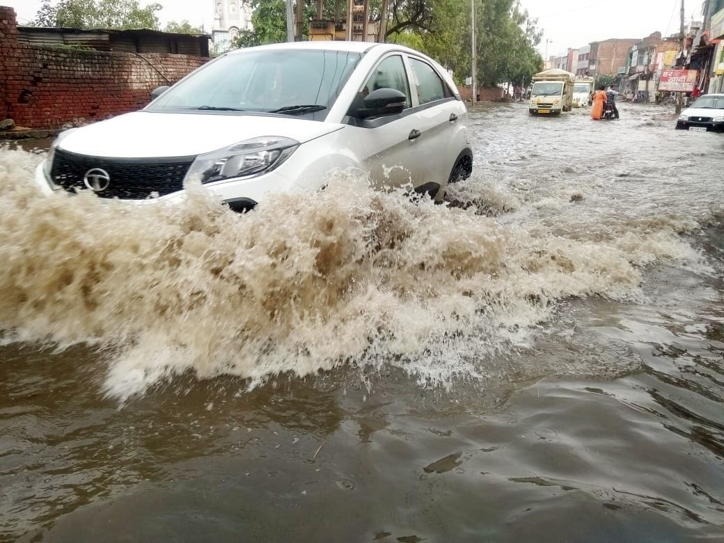 पुराना बस स्टेंड के सामने से गुजरने वाली सड़क पर भरे पानी से निकलती गाड़ी। संवाद पुराना बस स्टेंड के सामने से गुजरने वाली सड़क पर भरे पानी से निकलती गाड़ी। संवाद