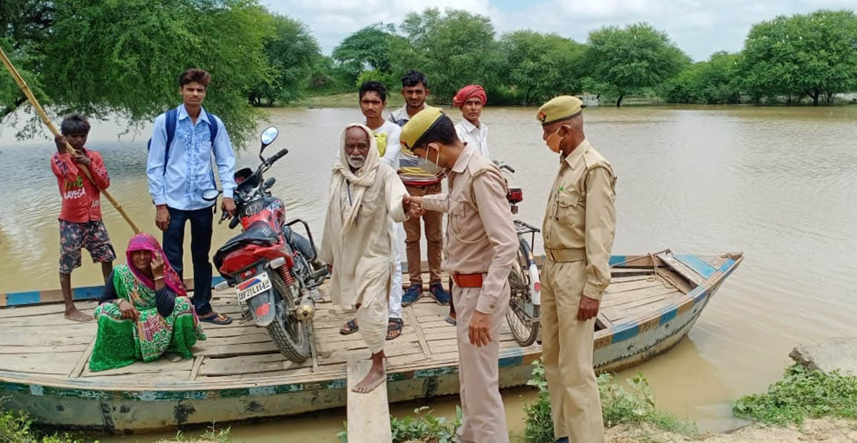 मौदहा क्षेत्र के गुढ़ा गांव के पास रपटे के ऊपर केन नदी का पानी भरने से नाव से आवागमन करते लोग।