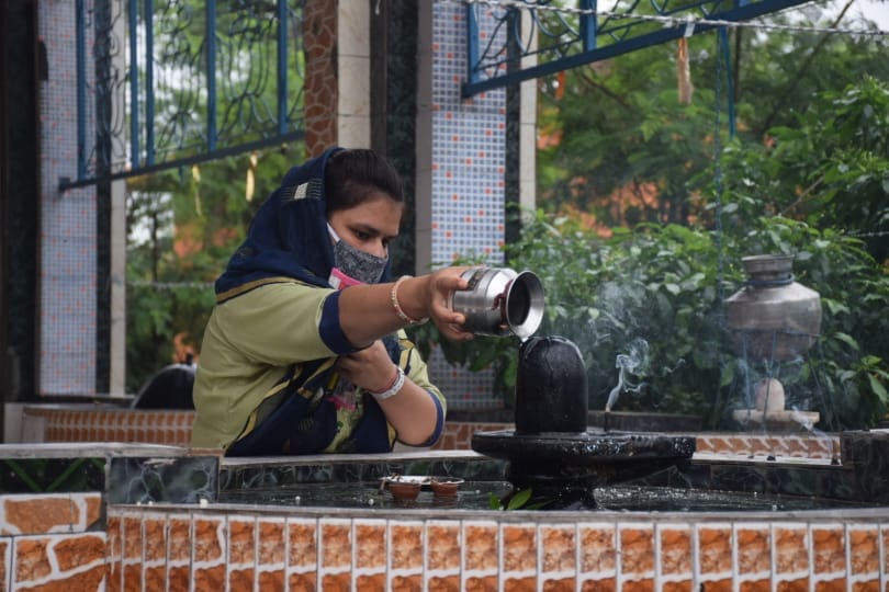 बागपत चमरावल रोड स्थित शिव मंदिर में सावन के तीसरे सोमवार को पूजा करती महिला