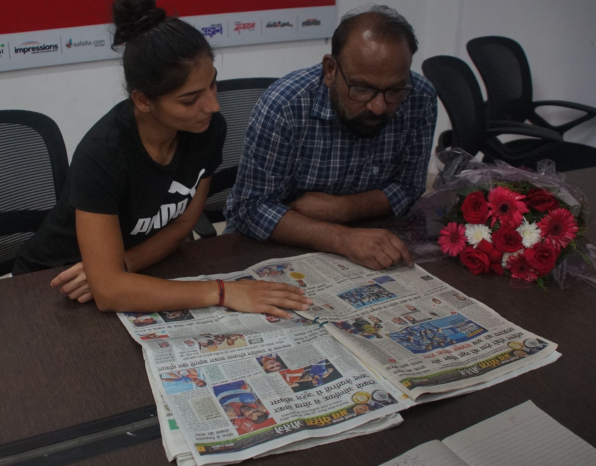 अमर उजाला कार्यालय में अखबार पढ़ते हॉकी खिलाड़ी उदिता और कोच आजाद मलिक।