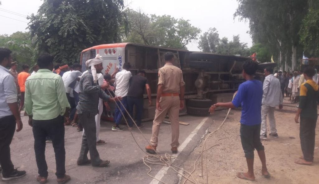 हाईवे पर पलटी बस को सीधा करते लोग। संवाद