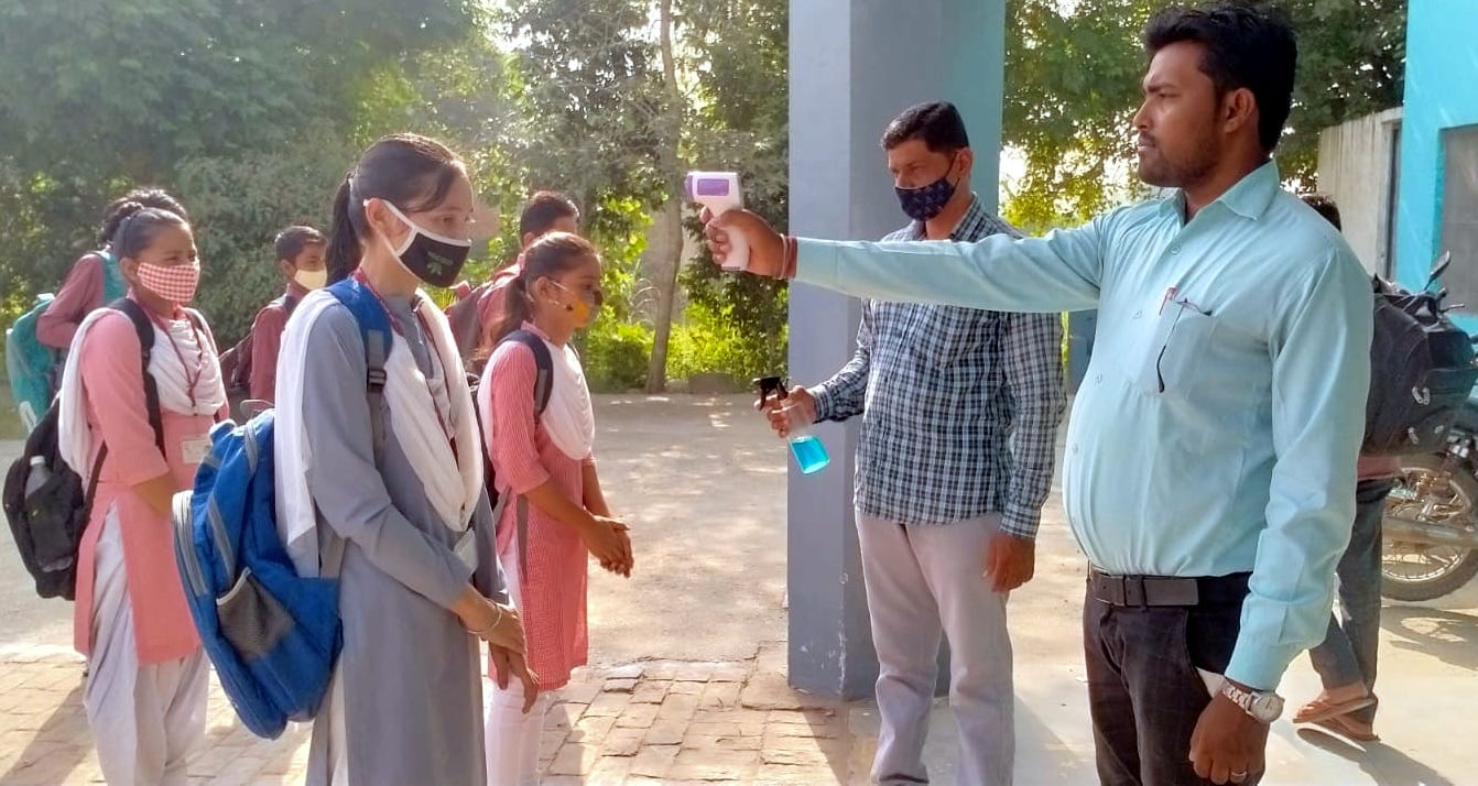 चौसाना में छात्राओ की  थर्मल स्कैनिंग व सैनिटाइज करते शिक्षक