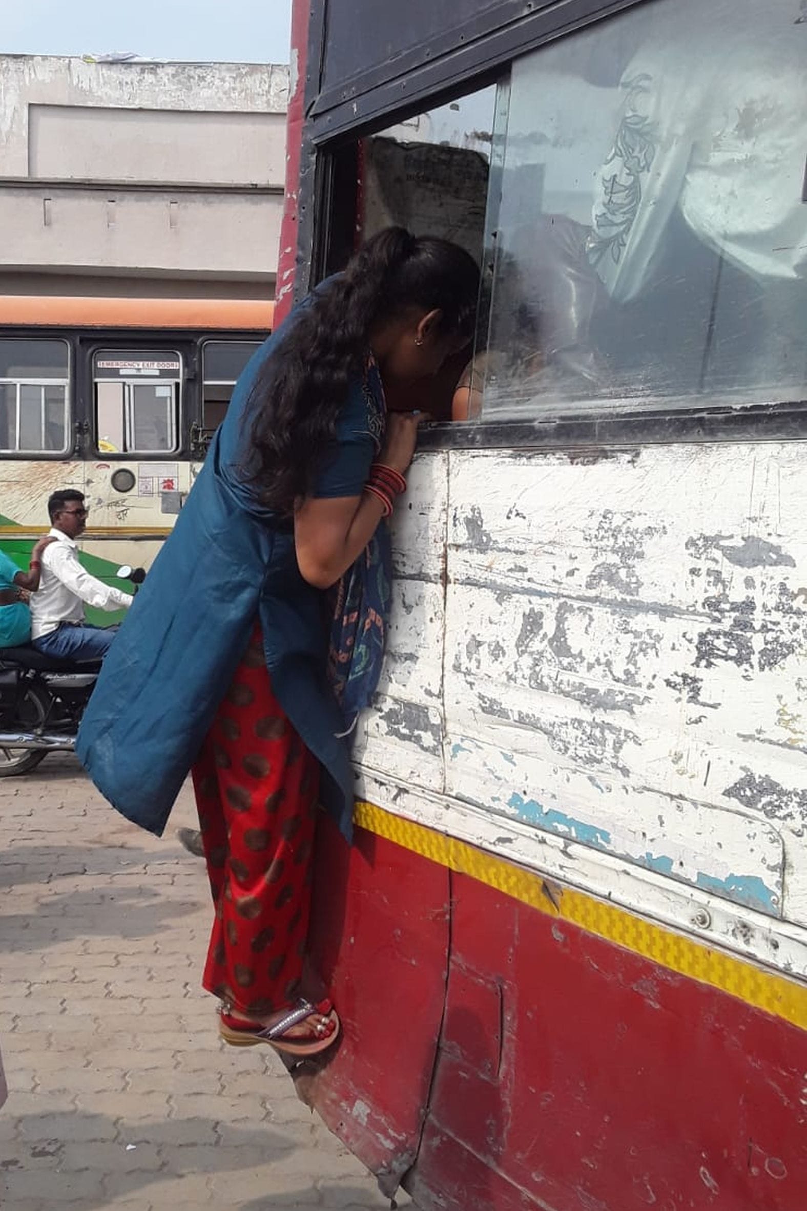 शहर के रोडवेज बस स्टैंड पर खिड़की से बस में चढ़ती महिला। संवाद