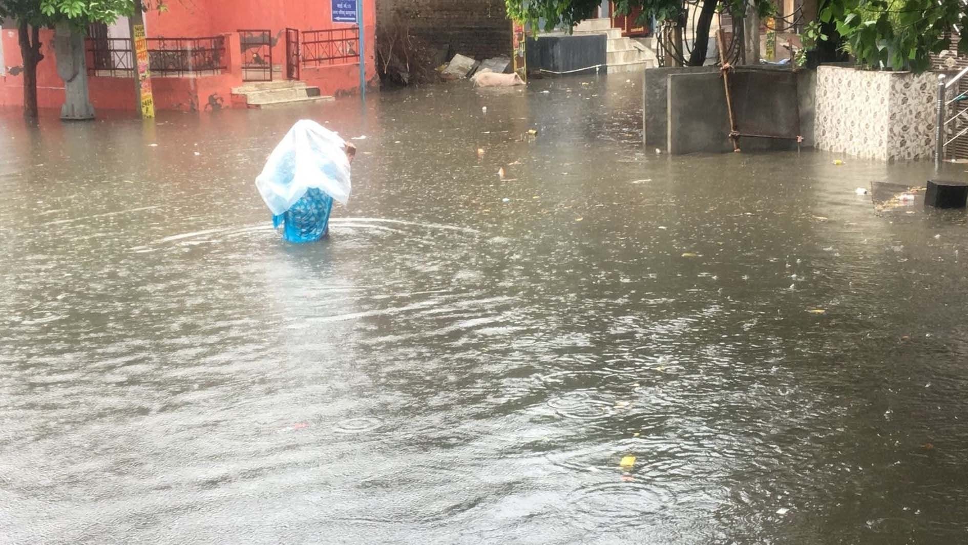   बाग वाला मौहल्ला की गलियों में जमा बारिश के पानी से गुजरती महिला।