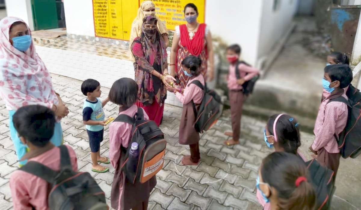 जैतपुर के प्राइमरी इंग्लिश मीडियम  विद्यालय में बच्चों को फूल देकर स्वागत करती शिक्षिका