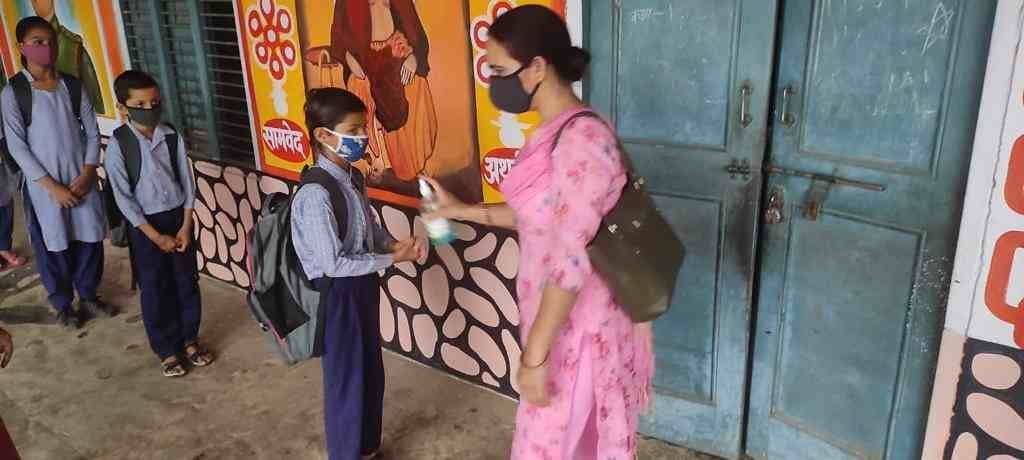 विद्यार्थियों के हाथ सैनिटाइज करवाती शिक्षिका। संवाद विद्यार्थियों के हाथ सैनिटाइज करवाती शिक्षिका। संवाद