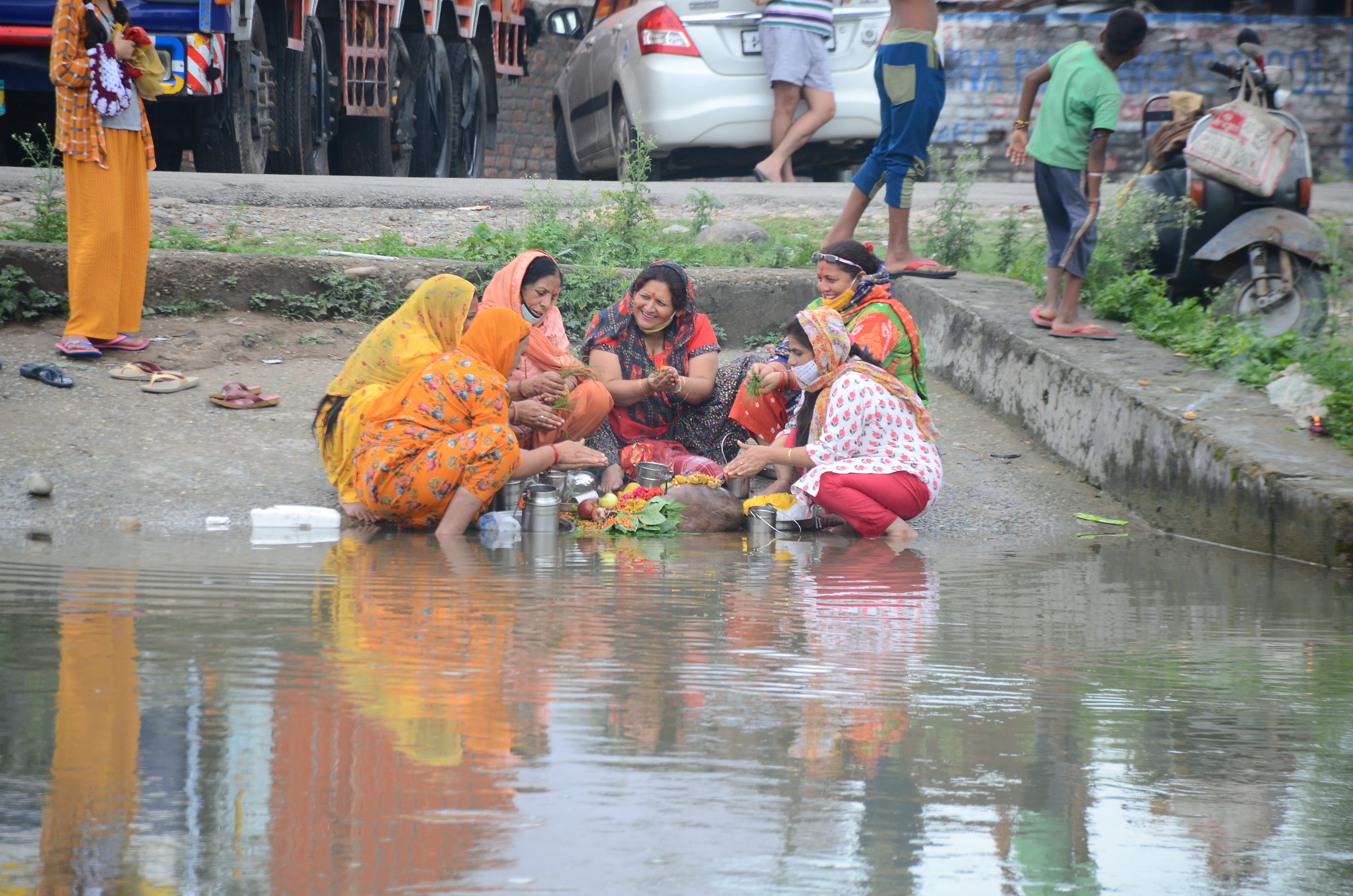 नहर के किनारे बच्छ दुआ की पूजा करती महिलाएं, संवाद।