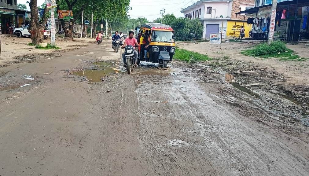 मुख्यमार्ग पर कीचड़ के बीच निकलते वाहन मुख्यमार्ग पर कीचड़ के बीच निकलते वाहन