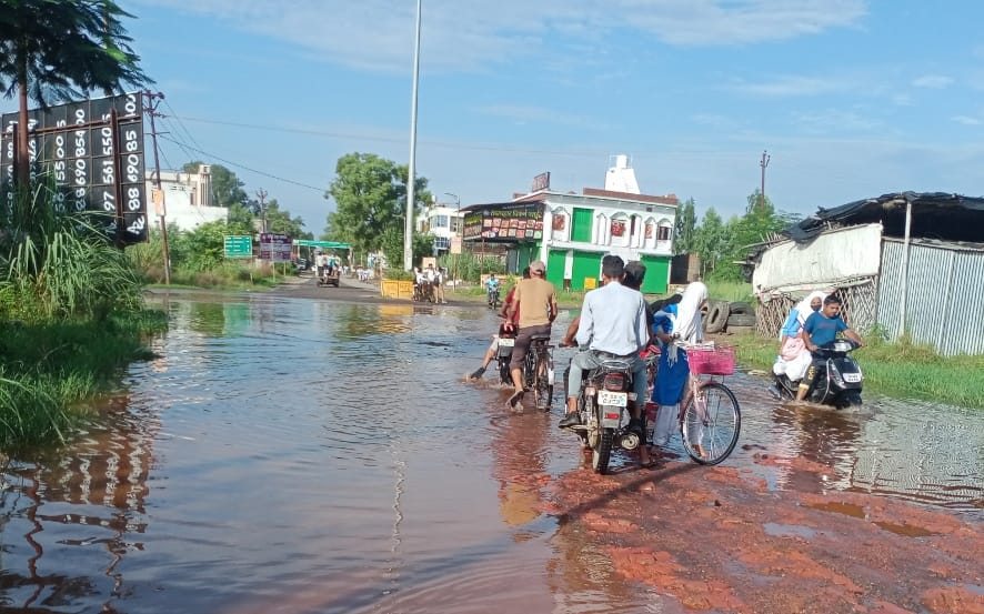 जलालाबाद में आजाद चौक मार्ग के जलभराव से गुजरते छात्र और राहगीर।
