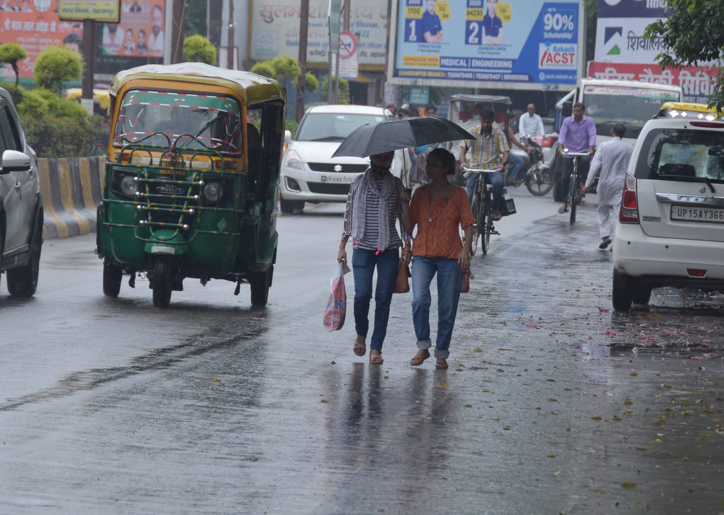 सहारनपुर में हुई बरसात में दिल्ली  रोड पर छाता लेकर जाती युवतियां