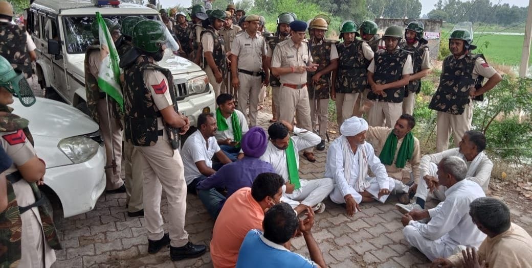सड़क पर बैठे किसान, किसानों को हटाने के लिए तैनात पुलिस बल।