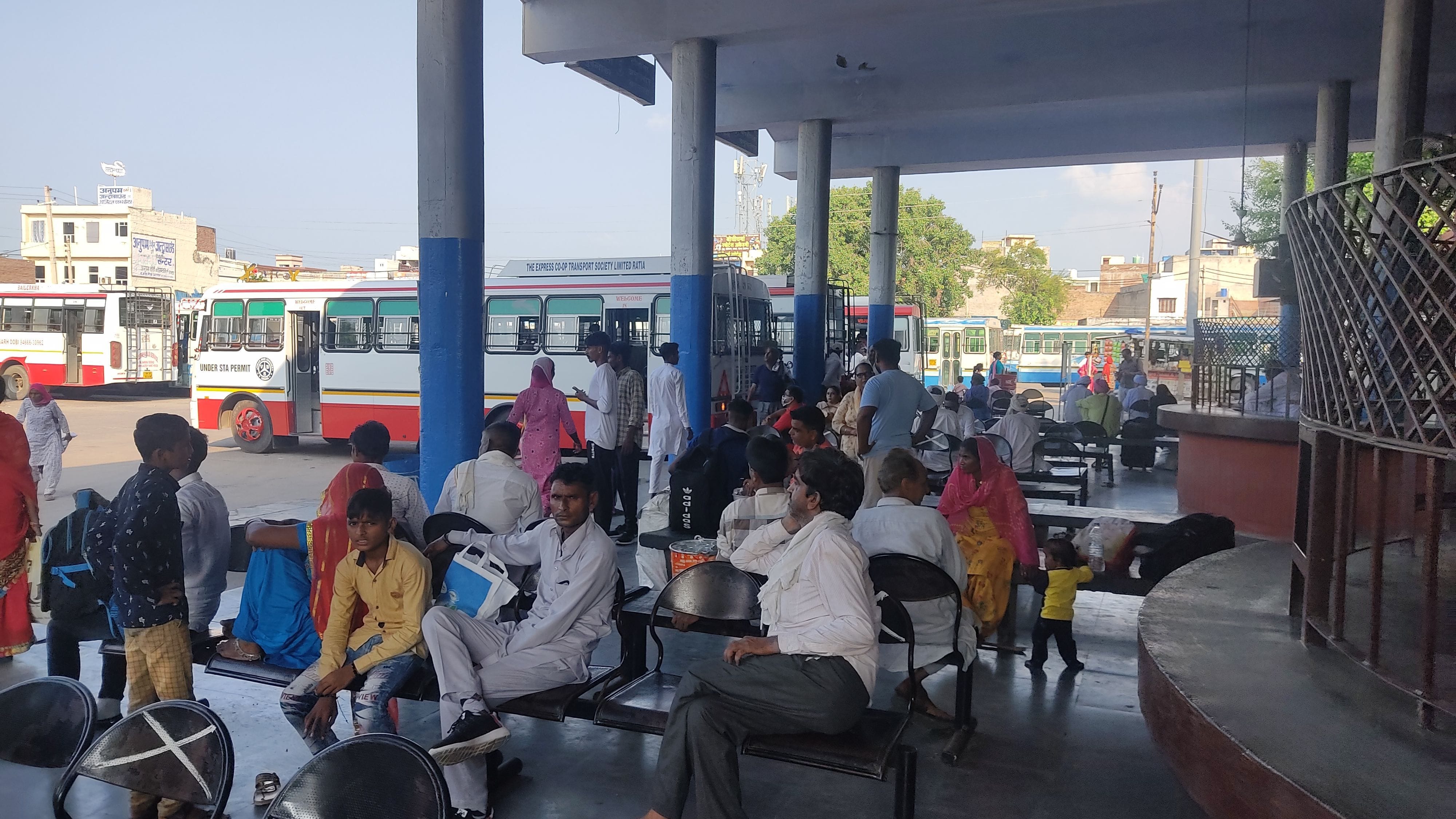 बस स्टैंड पर बस के इंतजार में बैठे यात्री। बस स्टैंड पर बस के इंतजार में बैठे यात्री।