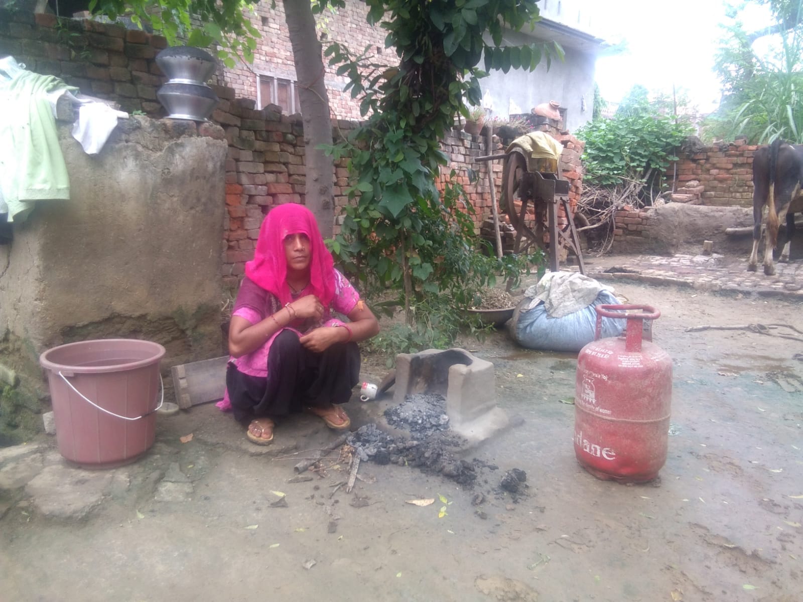 चुल्हे के पास बैठ खाली सिलेंडर दिखाती फतेहचंदपुर की बेबी चुल्हे के पास बैठ खाली सिलेंडर दिखाती फतेहचंदपुर की बेबी