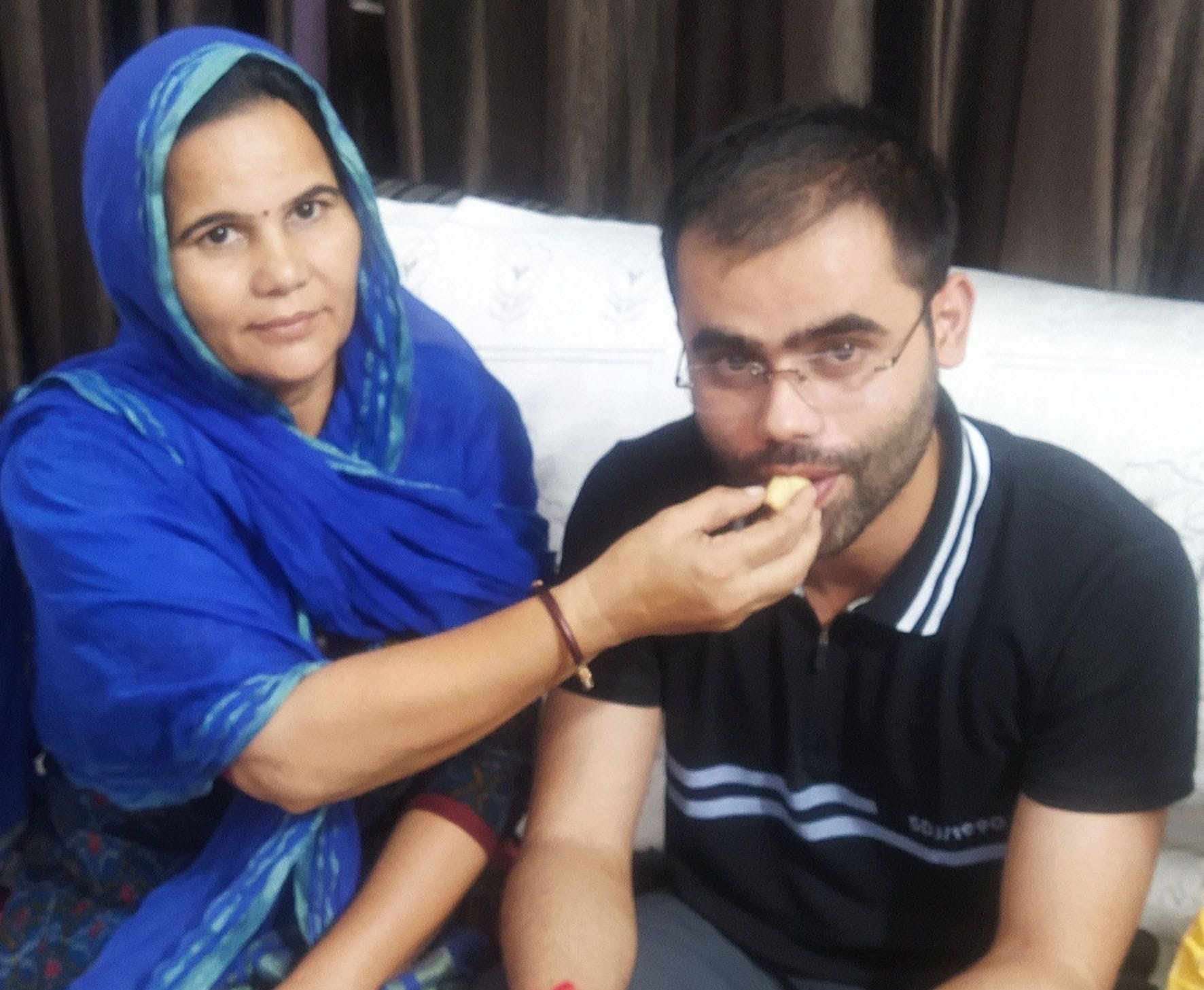 बेटे प्रिंस को मिठाई खिलाकर खुशी जताती मां अनुबाला देवी