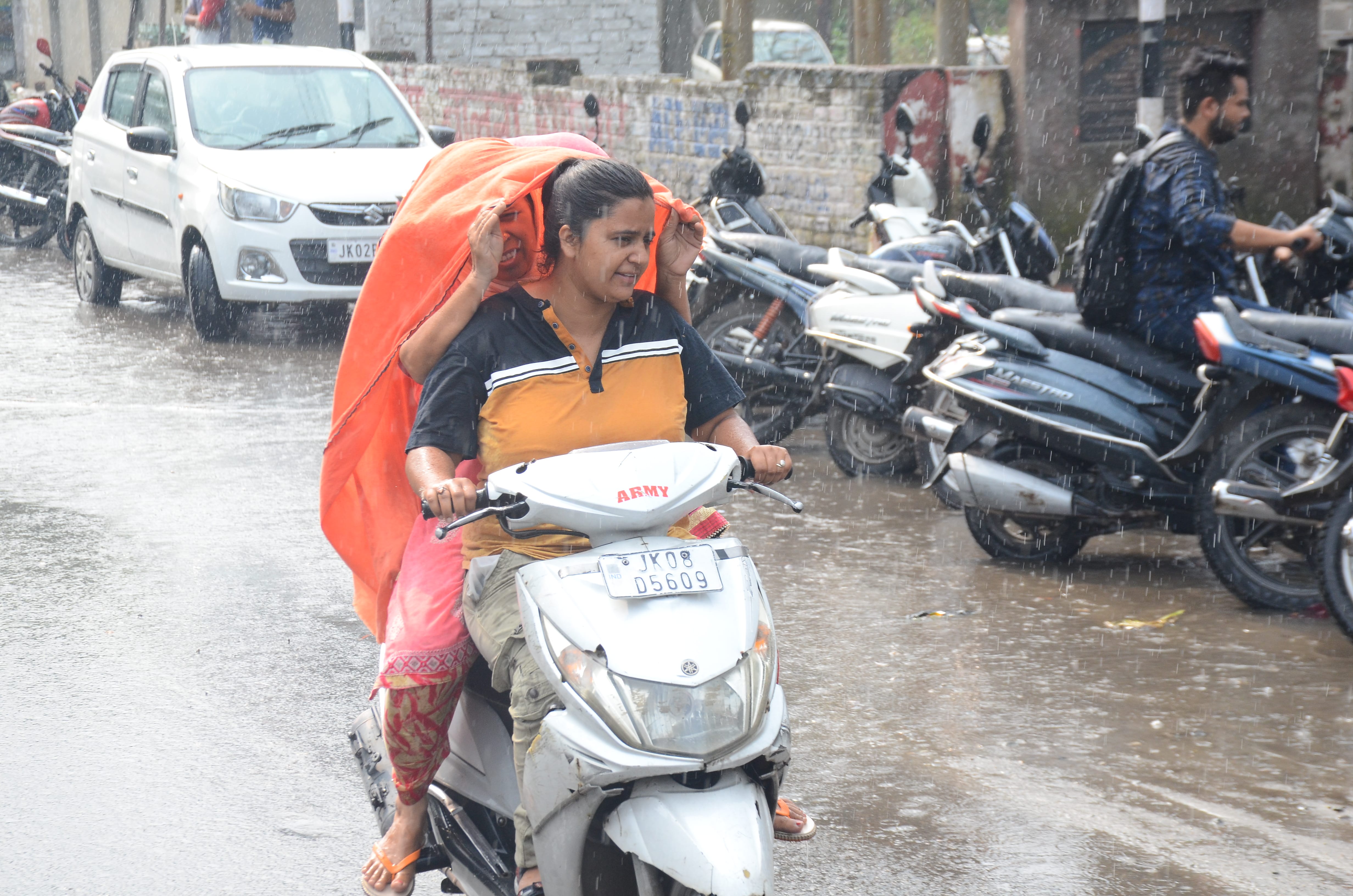 वीरवार सुबह हुई बारिश के दौरान बारिश से बचने का प्रयास करती स्कूटी चालक, संवाद। वीरवार सुबह हुई बारिश के दौरान बारिश से बचने का प्रयास करती स्कूटी चालक, संवाद।