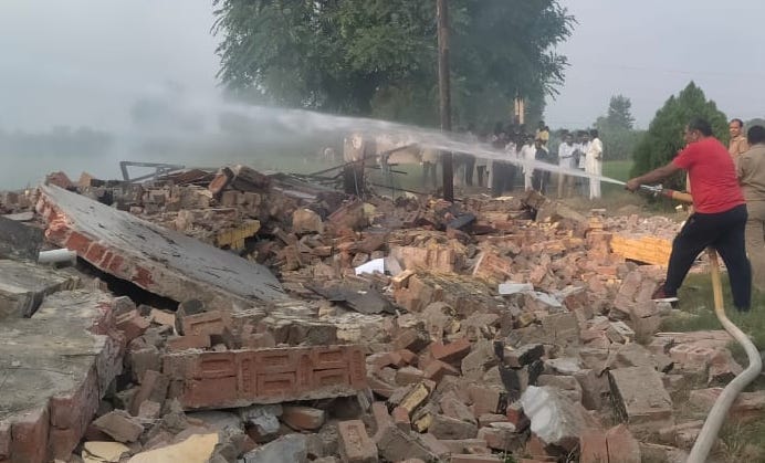 शामली के कैराना में अनाधिकृत पटाखा फैक्टरी में विस्फोट के बाद लगी आग को बुझाता  दमकल का कर्मचारी।