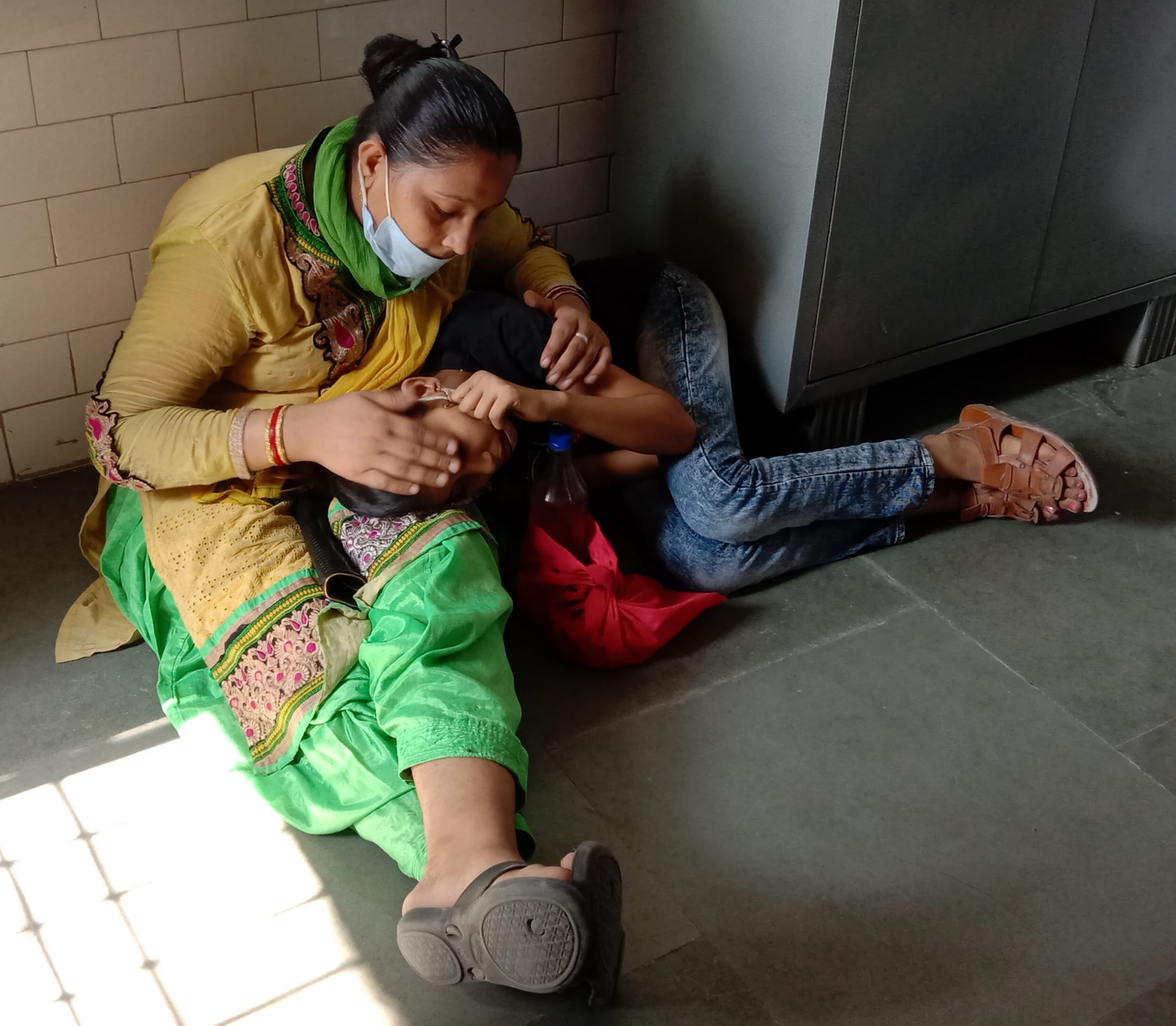 जिला अस्पताल की पैथोलॉजी लैब के सामने बुखार से पीड़ित बेटी को लिए मां।