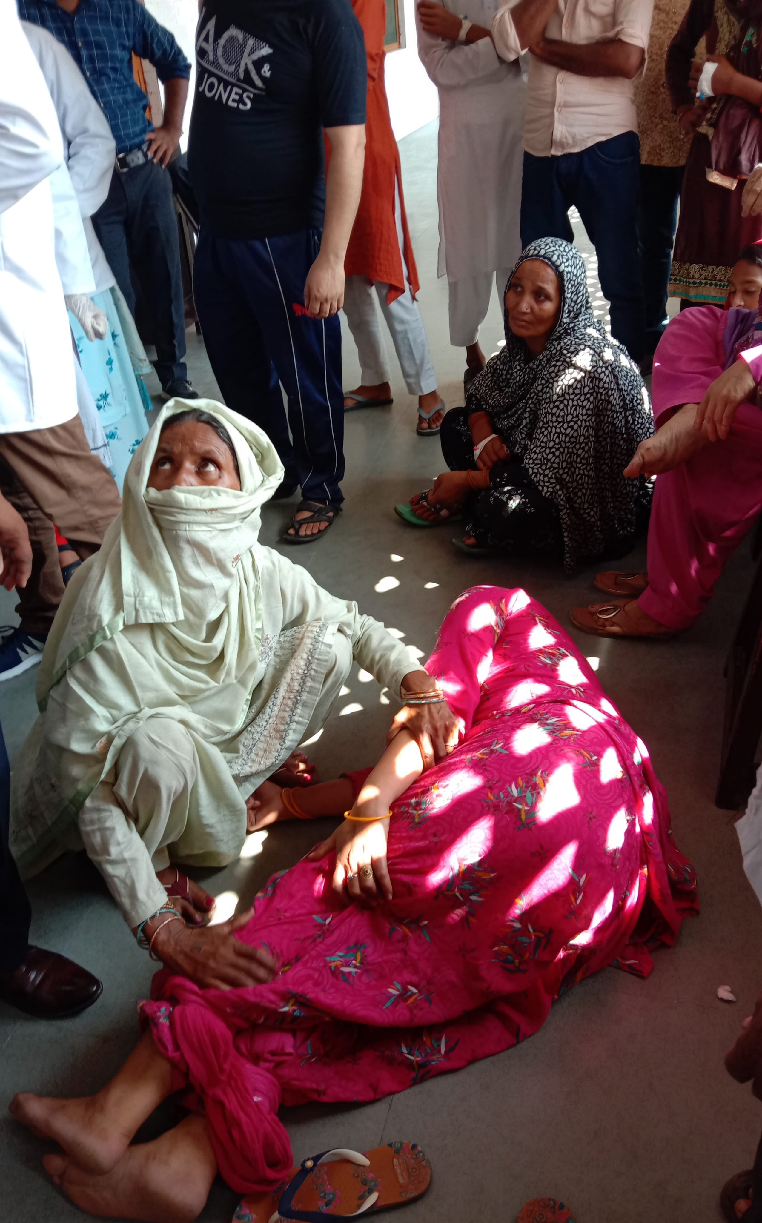 पैथोलॉजी लैब के बाहर बीमार महिला को संभालती महिला।