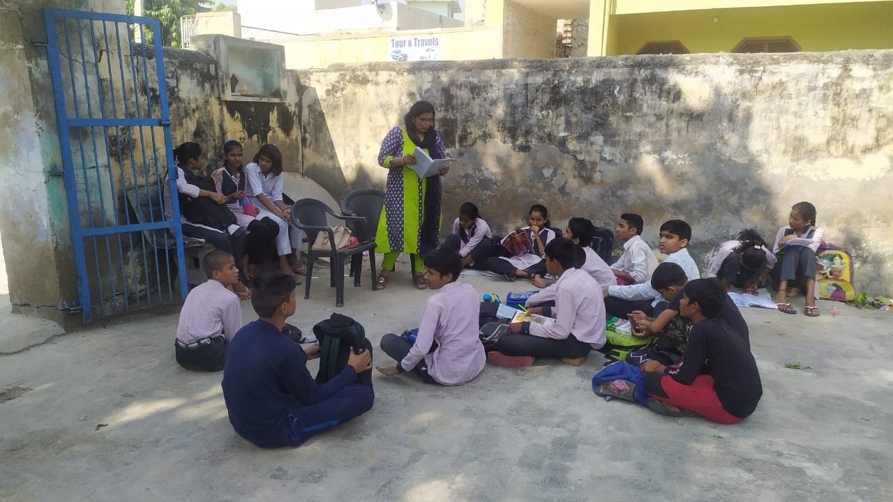  चौपाल में छात्रों को पढ़ाते अध्यापक।