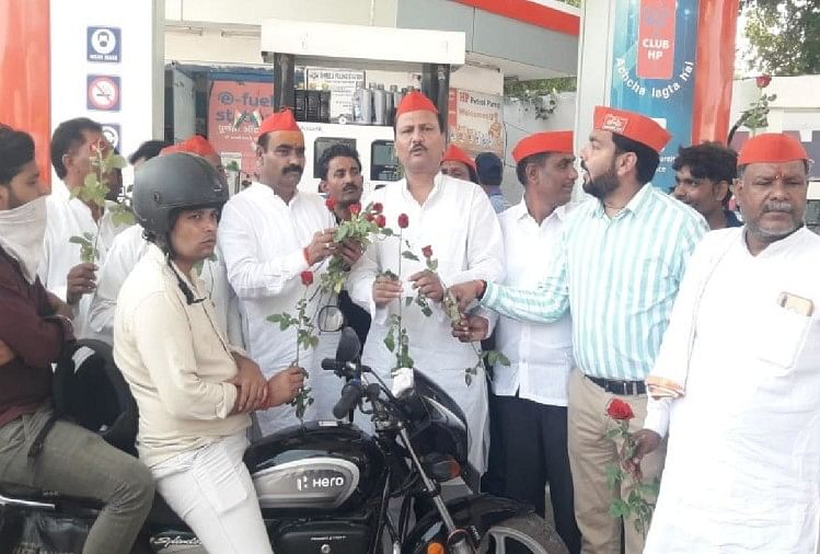 पेट्रोल पंप पर लोगों को फूल भेंट करते सपा नेता