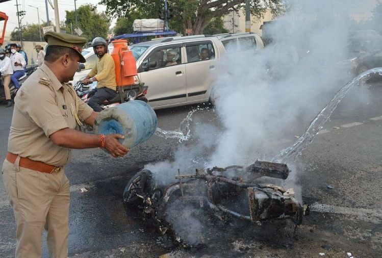 स्कूटर पर पानी डालकर आग बुझाता पुलिसकर्मी