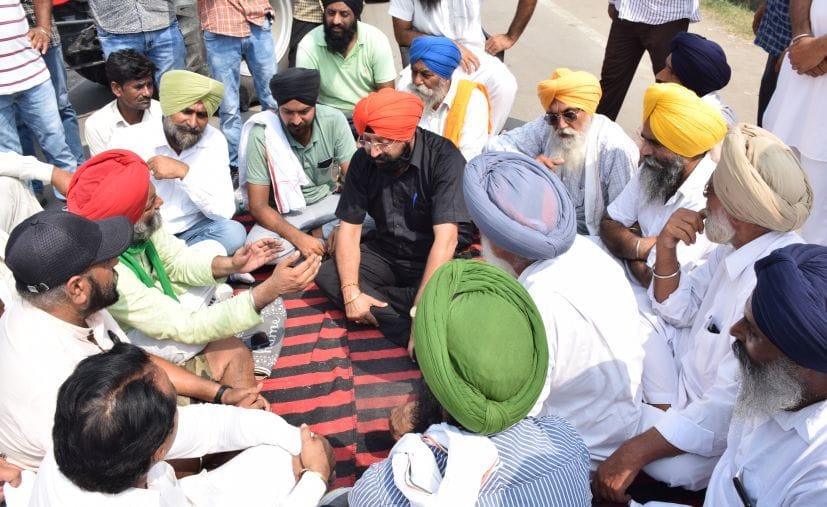 रुद्रपुर गल्ला मंडी रोड पर धरना देते किसानों को समझाते आरएफसी कुमाऊं हरबीर सिंह।