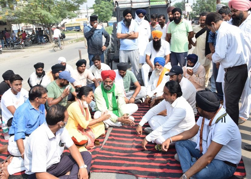 रुद्रपुर गल्ला मंडी रोड पर धरने पर बैठे किसानों को समझाती मंडी सचिव आशा गोस्वामी।