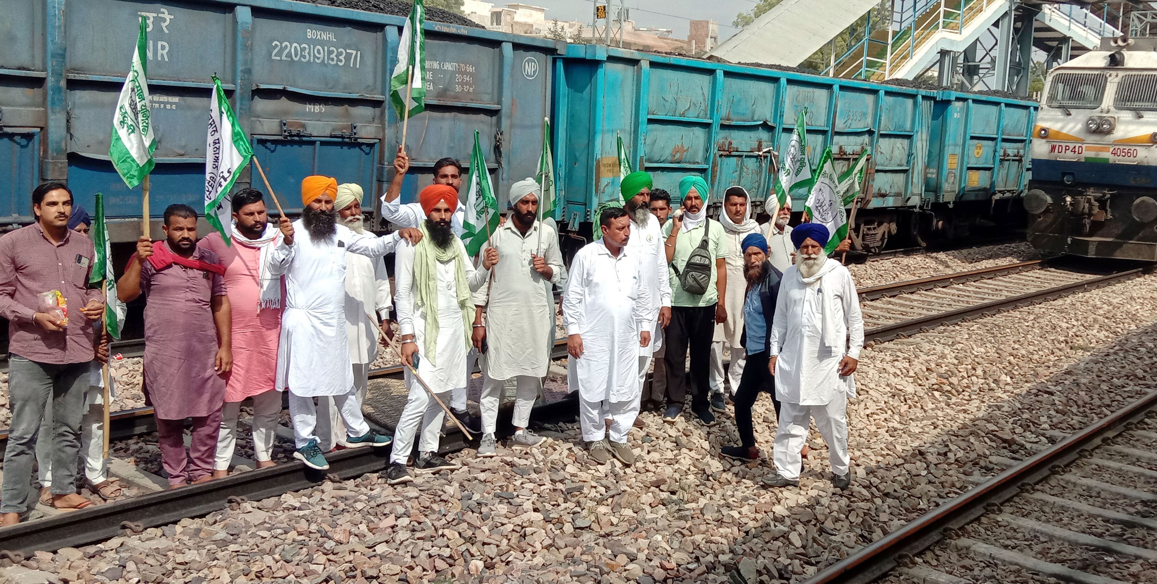 रेलवे ट्रैक पर गाड़ी के आगे खड़े होकर नारेबाजी करते किसान।